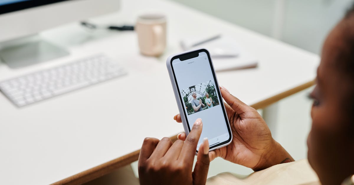 Close-up of hands using a smartphone at a desk with a computer. Ideal for tech and lifestyle content.