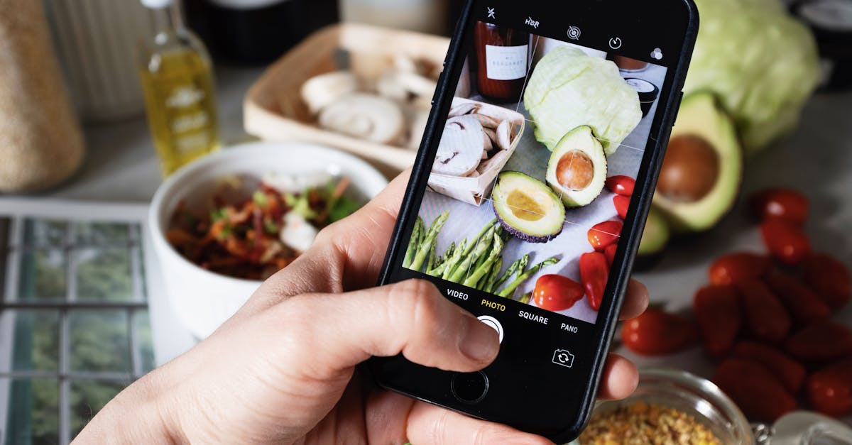 Photographing a healthy meal setup with various fresh vegetables using a smartphone.