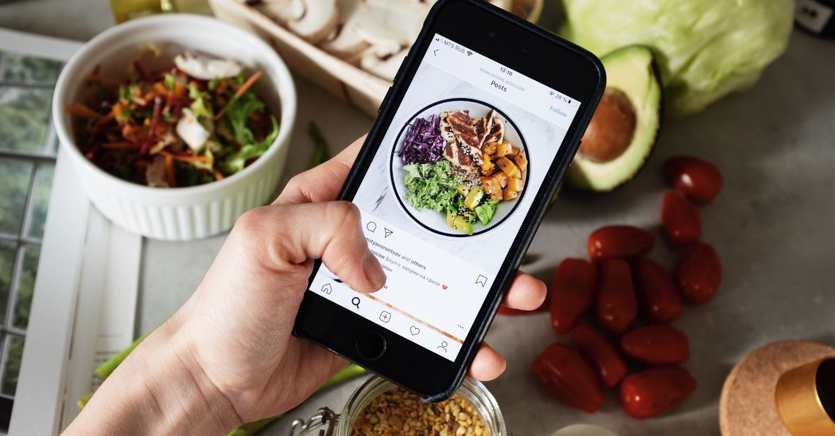 Person takes photo of healthy salad ingredients for social media in kitchen.