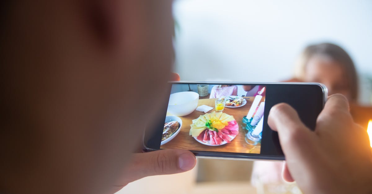 Close-up of a person taking a photo of a colorful food platter with a smartphone indoors.