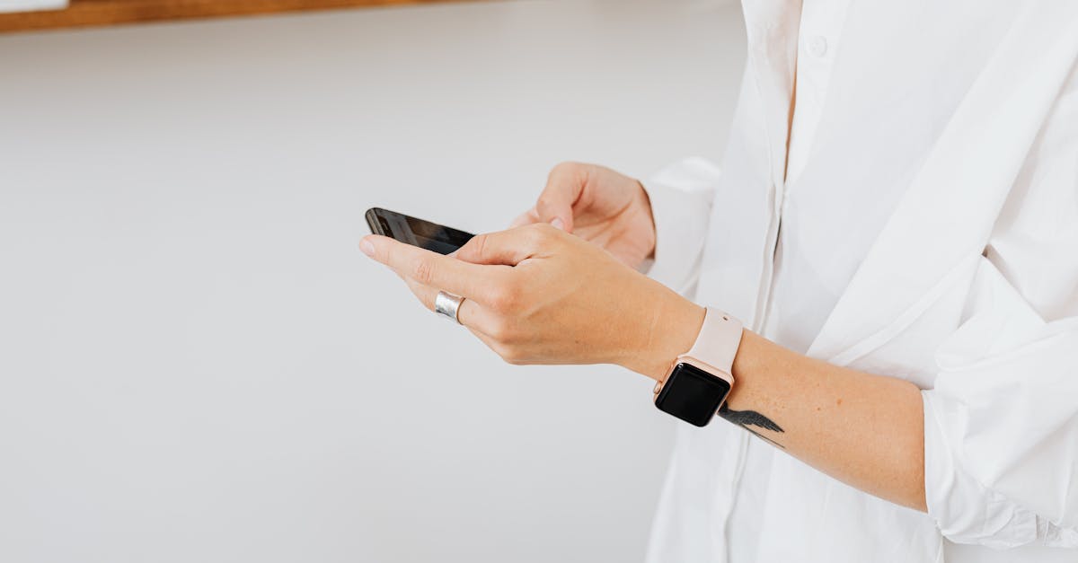 Close-up of person in white shirt using smartphone, wearing a smartwatch.