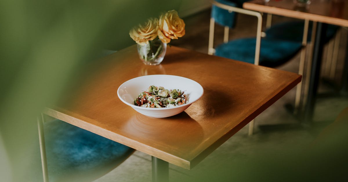 A fresh salad bowl on a wooden table in a cozy cafe setting, accented with vibrant floral decor.