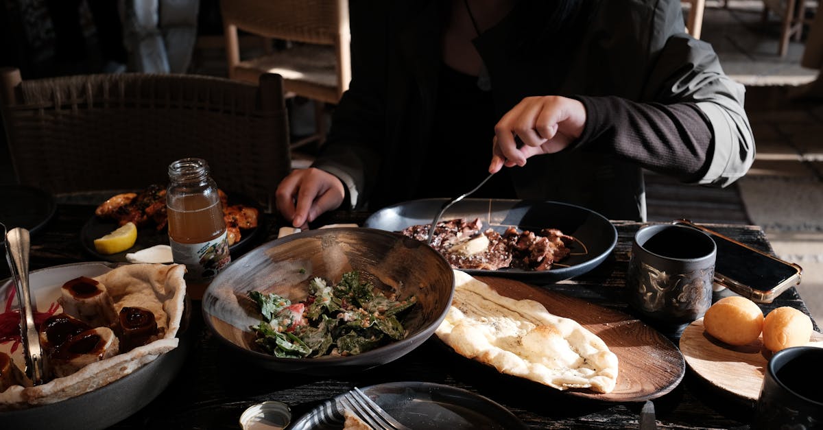 A person enjoys a meal with diverse dishes on a wooden table in a cozy restaurant.